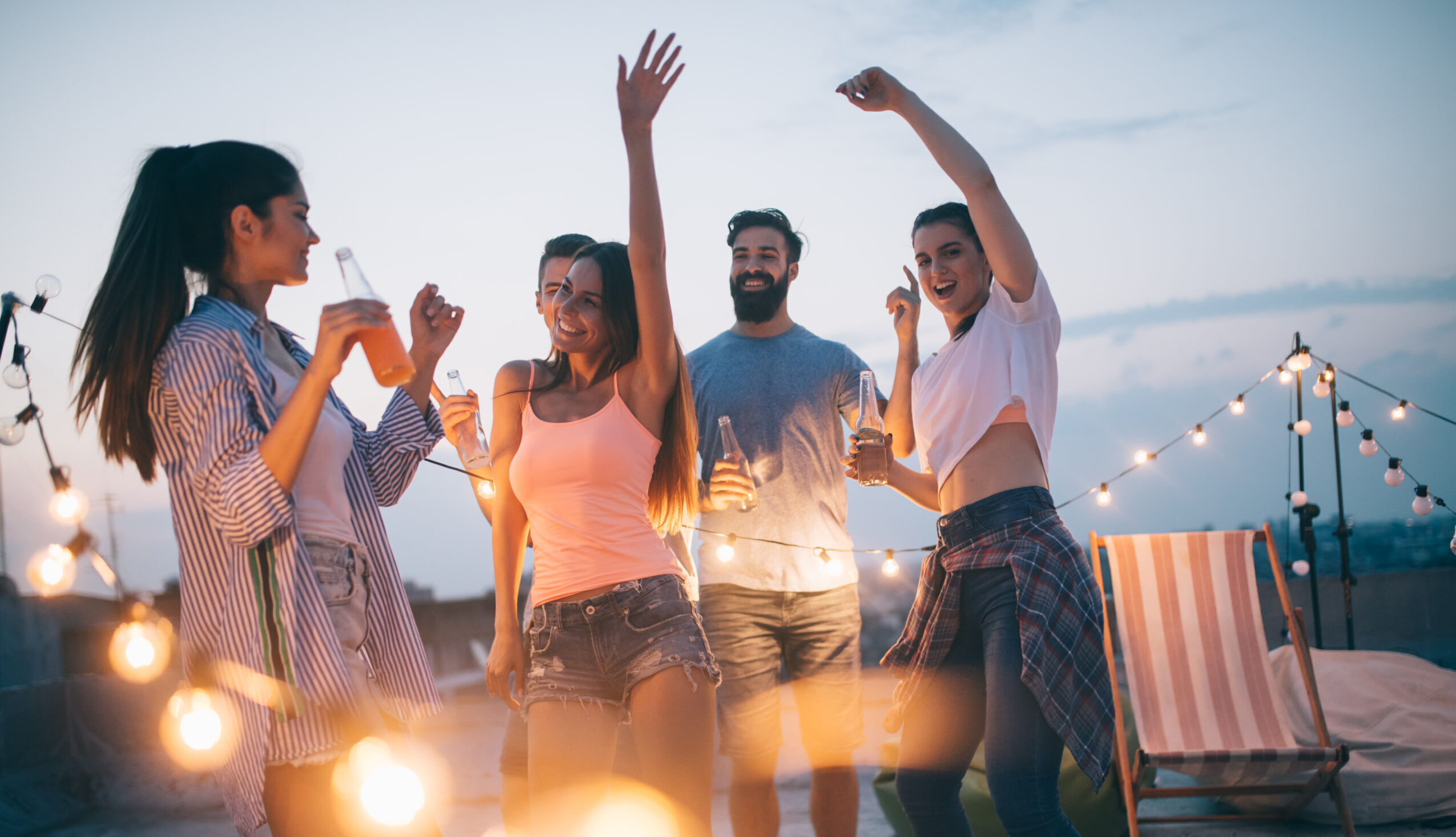 Happy friends having party on top of the roof . Fun, summer, city lifestyle and friendship concept